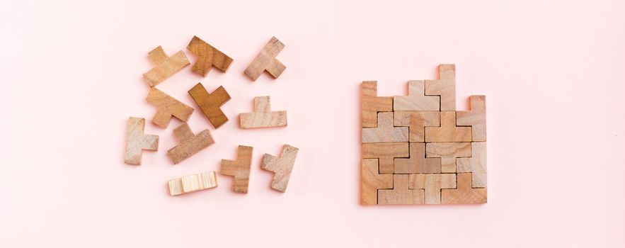 Organization and order. Wooden puzzle pieces are stacked correctly and chaotically scattered in disarray on a pink background. Web banner
