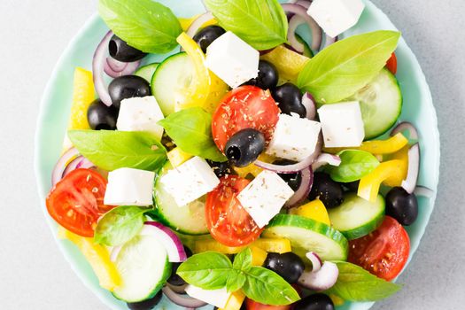 Fresh homemade greek salad with basil leaves on a plate on the table. Domestic life. Top view. Close-up