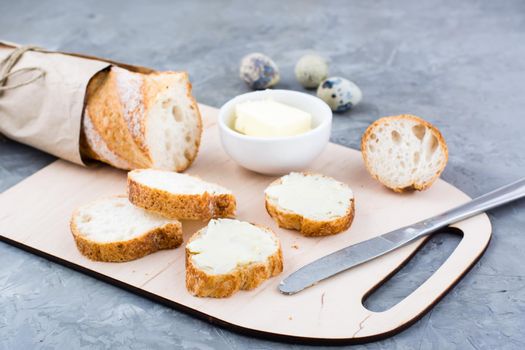 Tasty breakfast. Fresh baguette sandwiches with butter and quail eggs on a cutting board on the table