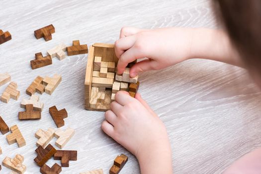 Organization and order. The child folds the wooden puzzle pieces into a folding mold. Leisure for children