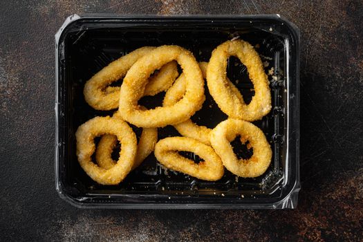 Raw Crispy deep fried onion or Calamari ring plastic pack set, on old dark rustic table background, top view flat lay