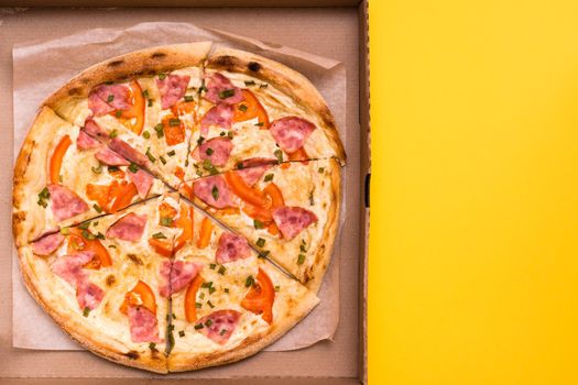 Takeaway and delivery. Ready-to-eat pizza in cardboard box on yellow background. Copy space