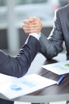 handshake business partners after the conclusion of successful contract on the background of the workplace