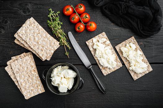 Crispbreads with feta set, on black wooden table background, top view flat lay