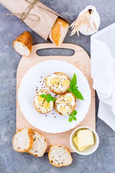 Hearty breakfast in the morning. Fresh baguette sandwiches with butter, quail eggs, flax seeds and basil seeds on a plate on the table. Top and vertical view