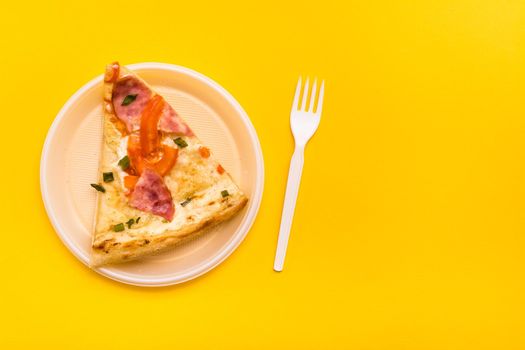 Takeaway and delivery. Pizza slice in disposable plastic plate and fork on yellow background