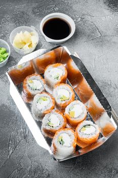 Variety of different sushi and rolls fro, salmon and tuna in delivery food concept set, on gray stone background