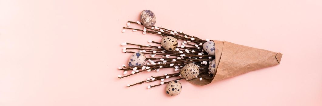 Happy Easter. Bouquet of quail eggs and pussy willow branches wrapped in brown paper on pink background. Web banner