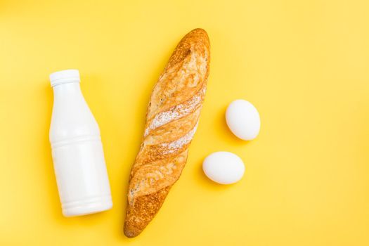 The minimum set of products for breakfast. Bread, eggs and milk on a yellow background