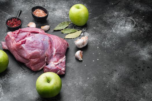 Raw pork meat with herbs set, on black dark stone table background, with copy space for text