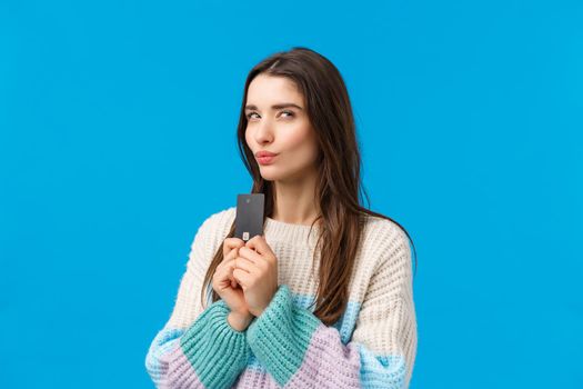 Thoughtful and sly attractive girl stole dads credit card and thinking how waste money, imaging something good, pondering what buy during winter shopping discount season, squinting mysterious.