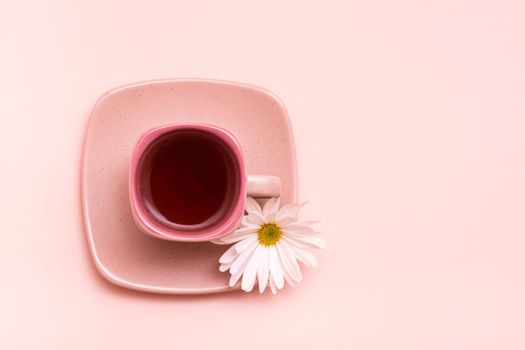 Pink concept. Square coffee cup with pink drink with flower on saucer on pink background. Top view