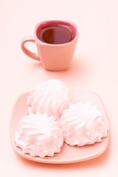The concept is pink. Pink drink in a coffee cup and marshmallows on a saucer on a pink background. Vertical view