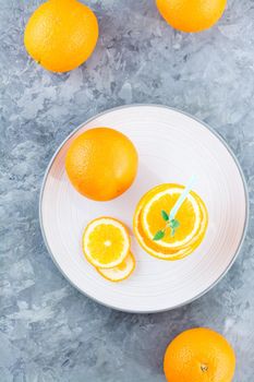 Fresh orange slices in a stack, mint leaves and a straw for a drink. Simulated orange juice. Top and vertical view. Healhy eating