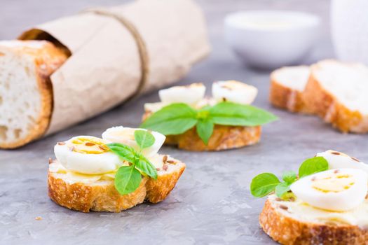 Hearty breakfast in the morning. Fresh baguette sandwiches with butter, quail eggs, flax seeds and basil seeds on the table