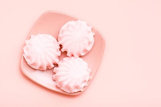 The concept is pink. Pink marshmallows on a saucer on a pink background. Top view
