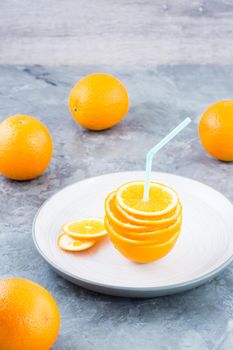Fresh orange slices in a stack and a straw for a drink. Simulated orange juice. Vertical view