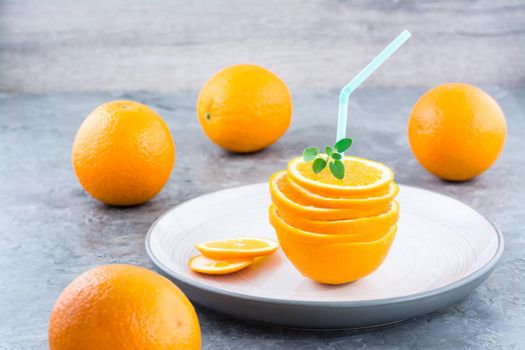 Fresh orange slices in a stack, mint leaves and a straw for a drink. Simulated orange juice