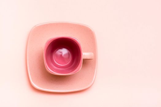 Pink concept. Empty square coffee cup on a saucer on a pink background. Top view