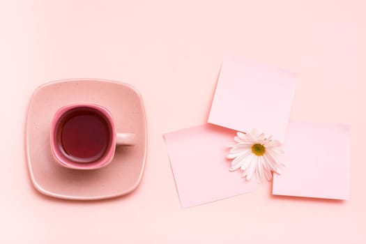 The concept is pink. Pink drink in a coffee cup, leaf for writing and chrysanthemum on a pink background. Top view