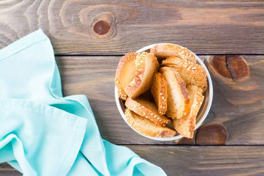 Small baguette toast in a bowl on a wooden table. Copy space. Top view