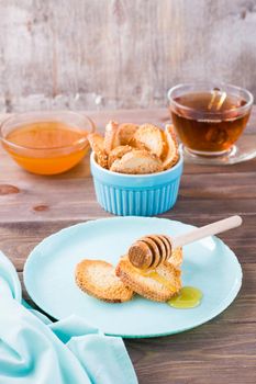 Small baked baguette toast with hot honey on a plate on a wooden table. Homemade tea. Vertical view