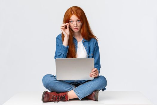 Excuse me what, I am busy. Questioned redhead female student interrupted during preparing project, searching material for class in internet, look curious camera, sitting on floor with laptop.