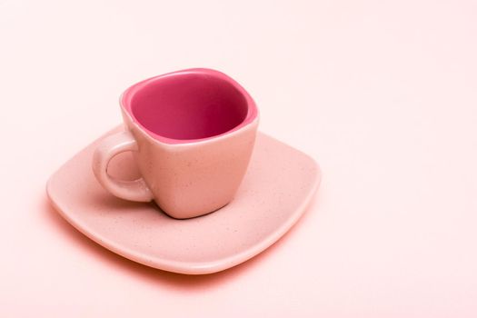 Pink concept. Empty square coffee cup on a saucer on a pink background