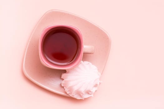 The concept is pink. Pink drink in a coffee cup and marshmallows on a saucer on a pink background. Top view