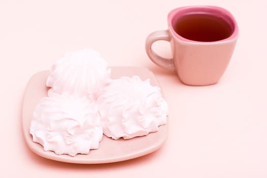 The concept is pink. Pink drink in a coffee cup and marshmallows on a saucer on a pink background. Copy space