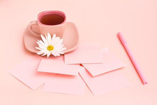 The concept is pink. Pink drink in a coffee cup, sheets for writing, a pen and a chrysanthemum on a pink background.