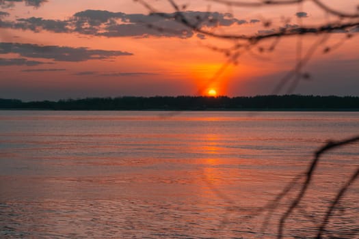 Sunset on the river on a summer evening. Calm water in the orange rays of the sun. Local tourism