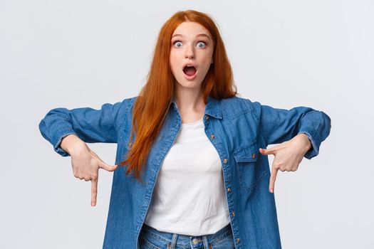 Omg look at that. Impressed and astounded alluring teenage girl found amazing new game in store, want it, express desire and temptation, stare surprised, pointing down with dropped jaw.