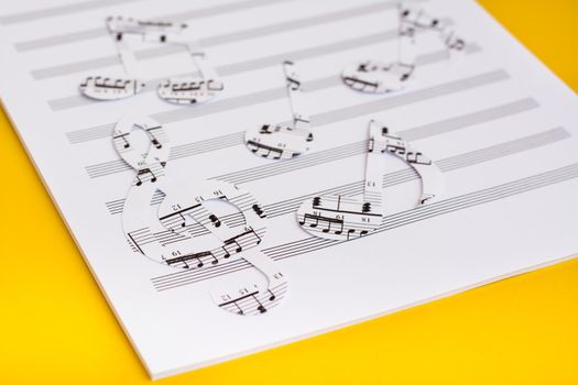 Blank sheet music and music notes cut from music text on yellow background