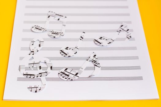 Blank sheet music and music notes cut from music text on yellow background. Copy space
