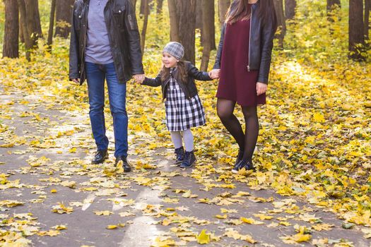 People, family and leisure concept - mother, father and little daughter have fun in autumn park.