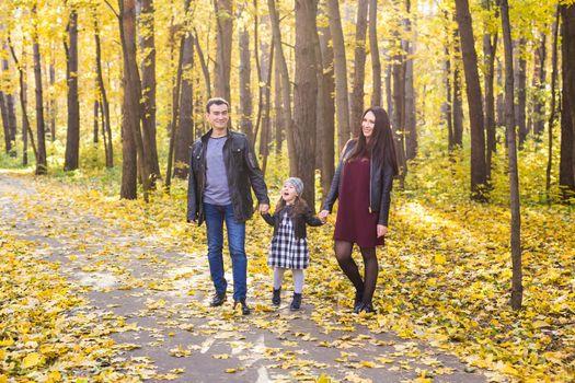 People, family and leisure concept - family standing in autumn park having fun.