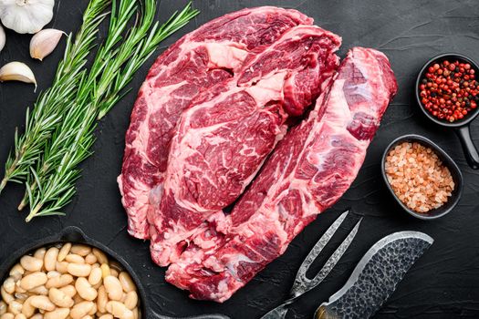 Legendary Ribeye fresh raw beef steak with spices and white beans set, on black stone background, top view flat lay