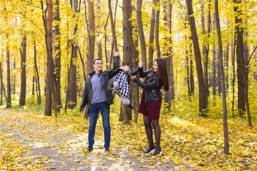 Family, fall, people concept - young family walking in park on in autumn day.