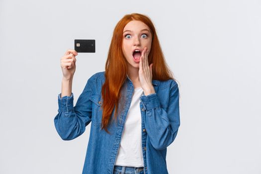 Amazing discounts, bank service concept. Waist-up portrait surprised and astonished good-looking redhead woman holding creding card, react amused to wonderful opportunity, giveaway.