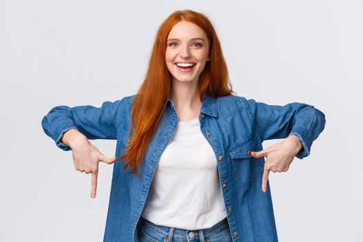 Must have, check this out. Waist-up portrait alluring, friendly redhead woman showing you good promo banner, review product, blogger indicate down, bottomg advertisement, white background.