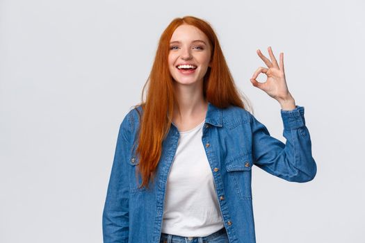 Waist-up portrait charismatic redhead woman having fantastic time with friends on party showing okay gesture, like or approve product, good service, laughing and smiling, white background.