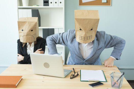 Business, emotions and people concept - Two angry and exhausted workers at working place. People wearing the packages on their heads with pictured emotions.