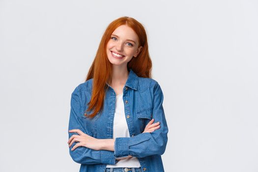 Professionalism, teamwork concept. Waist-up shot alluring pleasant redhead teenage, college student, female ginger girl in denim shirt, cross hands over chest and smiling happy, express confidence.