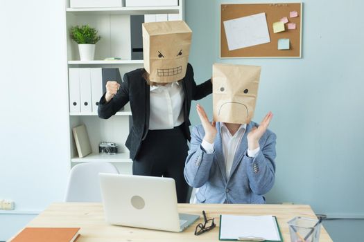 Business, emotions and people concept - Two angry and exhausted workers at working place. People wearing the packages on their heads with pictured emotions.