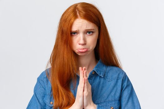 Pretty please. Close-up portrait sad, sulking cute redhead girl feeling guilty begging apology, pouting and frowning hopeful look camera, press hands together in pray, pleading over white background.