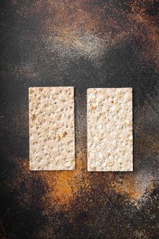 Stack of wholegrain crispy bread with sunflower, chia and sesames seeds set, on old dark rustic table background, top view flat lay, with copy space for text