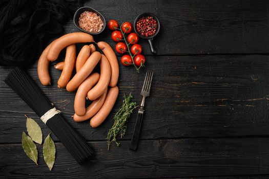Raw frankfurter sausages set, on black wooden table background, top view flat lay, with copy space for text