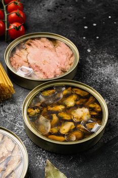 Canned fish and seafood in aluminum can set, on black dark stone table background