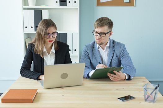 Business, teamwork and people concept - woman and man are working together in office.